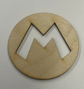 A wooden disk with the classic Mario "m" cut-out of the center, placed on a white surface.